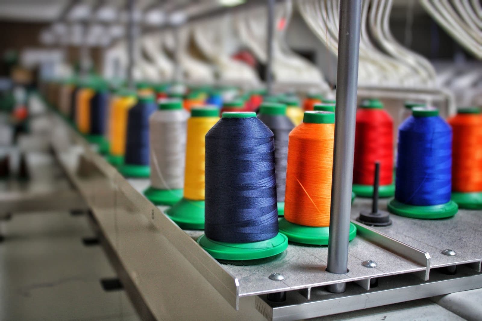 Cones de linha industrial alinhados em uma máquina de costura de produção